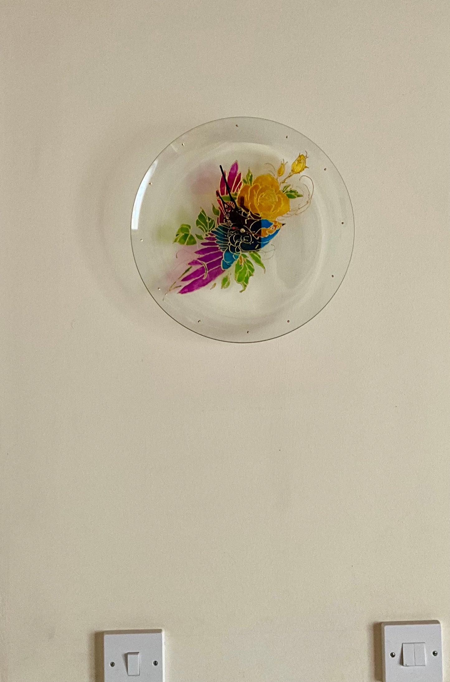 This unique painted glass clock features an original design of a vibrant bird and roses on a circular glass plate. The intricate hand-painting adds a touch of elegance and charm to any living space. Not only does it serve as a functional timepiece, but also as a beautiful piece of art.