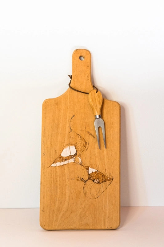Beach wood cheese board , wood-burnt with two profile faces about to kiss with hidden celestial objects. With attached cheese fork.