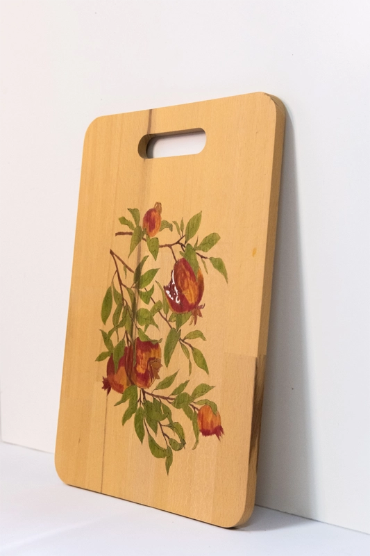 Beachwood chopping board woodburnt with a picture of Pomegranates hanging from branches, finished in acrylic.  14” x 9”. 36cm x 23cm