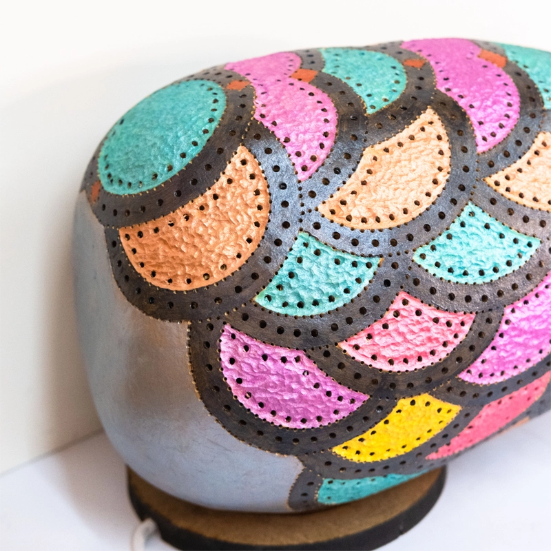 Gourd lamp wood-burnt, carved and decorated with metallic acrylics as the body of an Indian elephant with a ceramic head. 20cm tall.