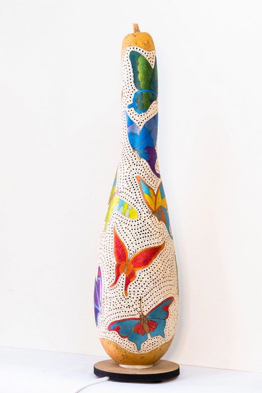 'A tall bodied gourd lamp, depicting different types and coloured butterflies . Wood-burnt, carved and finished in acrylic. Mains powered. 54cm tall.