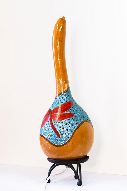 A gourd lamp depicting red dragonflies. Set on a black metal base. Wood-burnt, carved and finished in acrylics. Mains powered. 42cm tall.