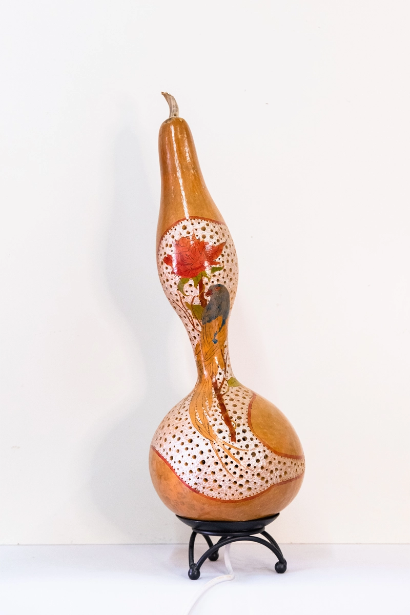 Gourd lamp featuring a bird on a rose. Wood-burnt, carved and finished n welburn inks on a metal tripod base. Mains powered. 49cm tall.